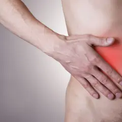 Mężczyzna trzyma się za bok, gdzie czerwony obszar sugeruje, że wątroba boli.